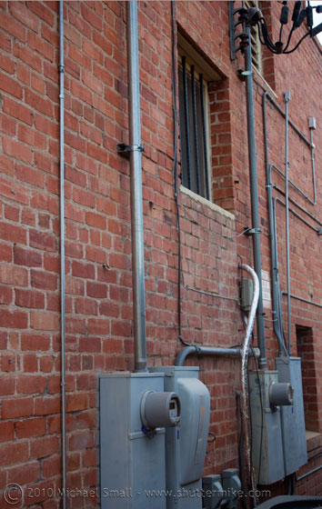 Photo of a brick wall with electrical panels and conduit.