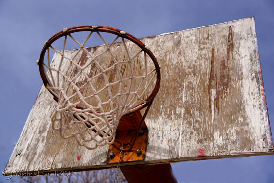 Photo of a weathered basketball hoop and backboard. 