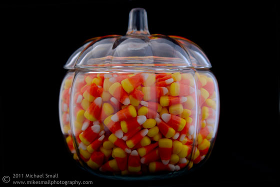 Photograph of candy corn in a glass pumpkin
