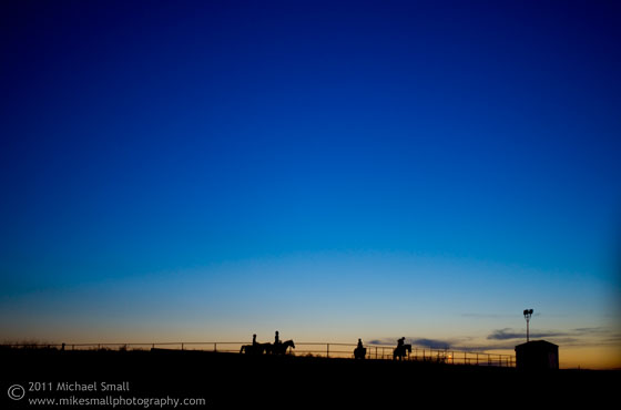 Photograph of horseback riders against the sunset